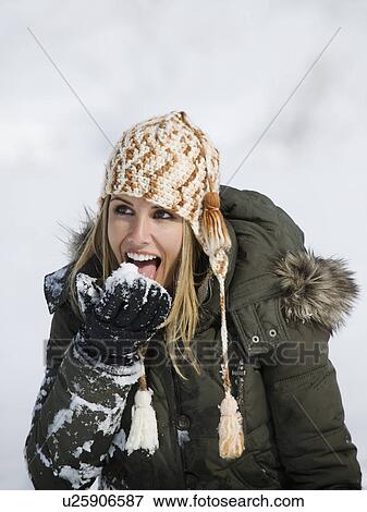 Stock Photo - A woman eating snow. Fotosearch