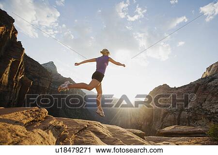 Stock Image - A woman jumping on rock at Red Rock. Fotosearch