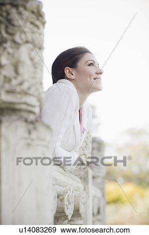 Stock Photo - A woman leaning on a railing outdoors. Fotosearch