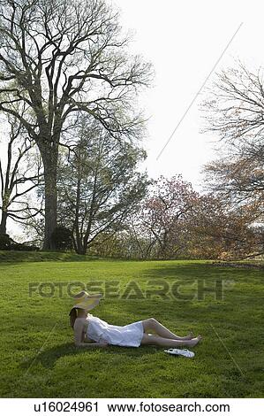 A woman lying on grass outdoors View Large Photo Image Stock Image - A woman lying on grass outdoors. Fotosearch