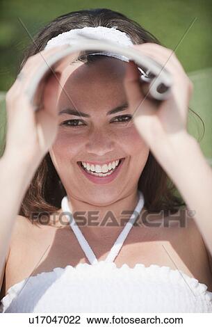 A woman outdoors shielding her eyes with a magazine View Large Photo Image Stock Image - A woman outdoors shielding her eyes with a magazine. Fotosearch