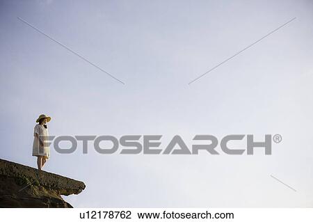 A woman standing on a cliff View Large Photo Image Stock Image - A woman standing on a cliff. Fotosearch