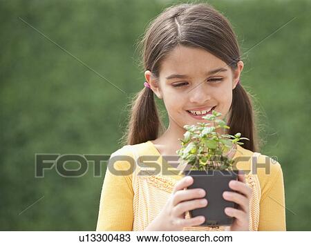 A young girl holding a plant View Large Photo Image Stock Image - A young girl holding a plant. Fotosearch