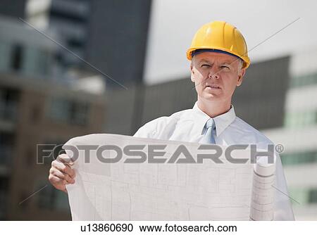 Stock Image - An architect holding plans outdoors. Fotosearch
