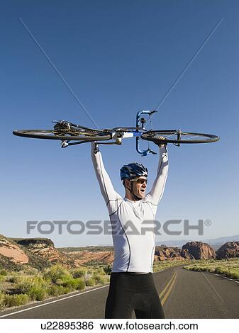 Biker on the road holding bike up View Large Photo Image Stock Photograph - Biker on the road holding bike up. Fotosearch