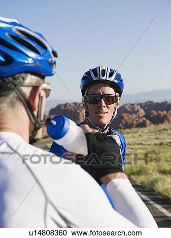 Stock Image - Bikers on the road taking a break drinking water. Fotosearch