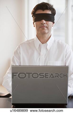 Stock Photo - Businessman using laptop while blindfolded. Fotosearch