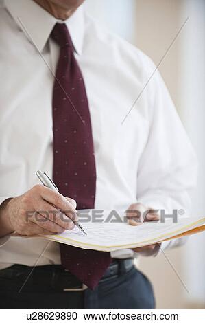Stock Image - Businessman writing on folder. Fotosearch