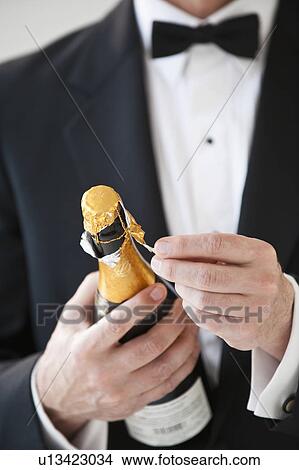 Champagne bottle being opened by a man in a tuxedo View Large Photo Image Picture - Champagne bottle being opened by a man in a tuxedo. Fotosearch