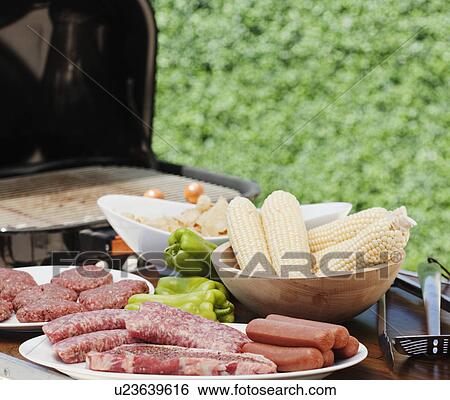 Stock Photograph - Corn and meats by a barbeque. Fotosearch