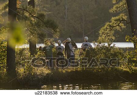 Stock Photo - Four construction workers by a lake with tools. Fotosearch