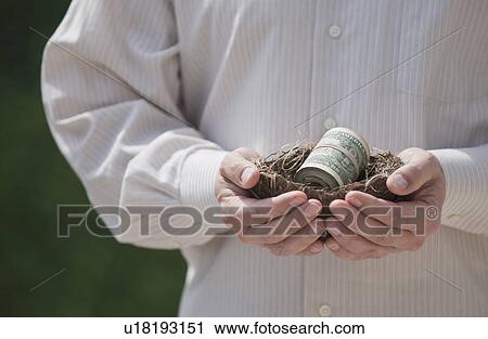 Stock Image - Hands holding a nest with money in it. Fotosearch