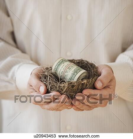 Stock Image - Hands holding a nest with money in it. Fotosearch