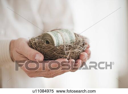 Stock Photography - Hands holding a nest with money in it. Fotosearch