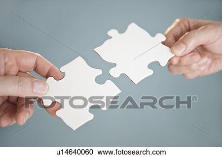 Stock Image - Hands holding puzzle pieces. Fotosearch