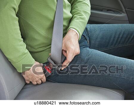 Stock Image - Man buckling seat belt in car. Fotosearch