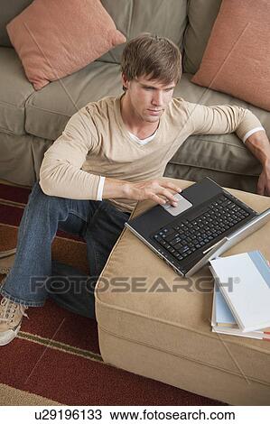 Man using laptop in living room View Large Photo Image Stock Image - Man using laptop in living room. Fotosearch