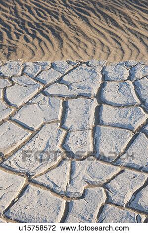 Stock Image - Sand dunes in the desert with cracked earth. Fotosearch