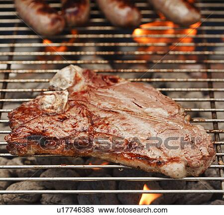 Stock Image - Steak and sausages on a barbeque. Fotosearch