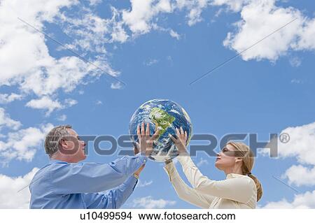Two people holding up a globe View Large Photo Image Picture - Two people holding up a globe. Fotosearch