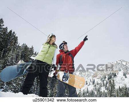 Two snowboarders pointing at sky View Large Photo Image Stock Image - Two snowboarders pointing at sky. Fotosearch
