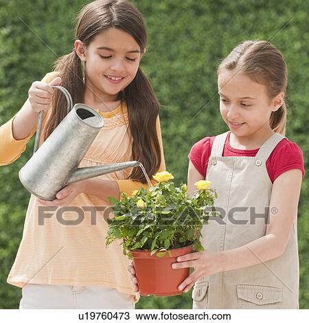 Stock Image - Two young girls watering a flower. Fotosearch