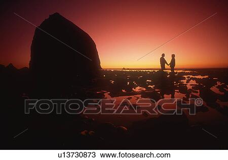 Stock Image - A couple silhouetted against the sunset. Fotosearch