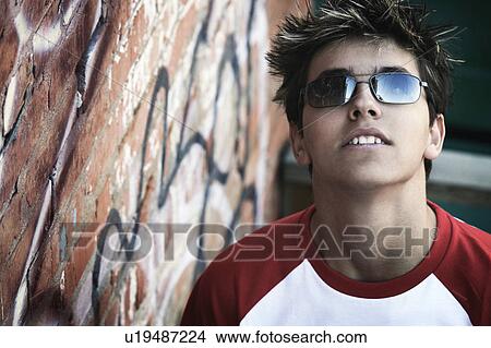 Picture - A teen by a wall of graffiti. Fotosearch