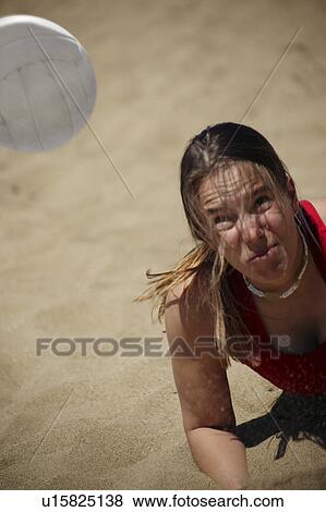 Stock Photo - A woman plays beach volleyball. Fotosearch
