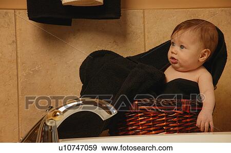 Baby sits in bathroom basket View Large Photo Image Stock Photo - Baby sits in bathroom basket. Fotosearch
