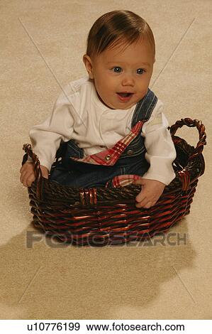 Baby sitting in a basket View Large Photo Image Stock Photo - Baby sitting in a basket. Fotosearch