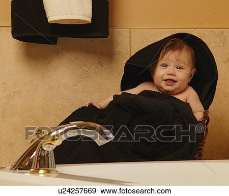 Stock Photo - Baby wrapped in towel in bathroom. Fotosearch