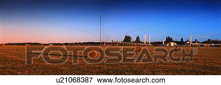 Stock Photo - Bales of hay in field with pumping station in background. Fotosearch