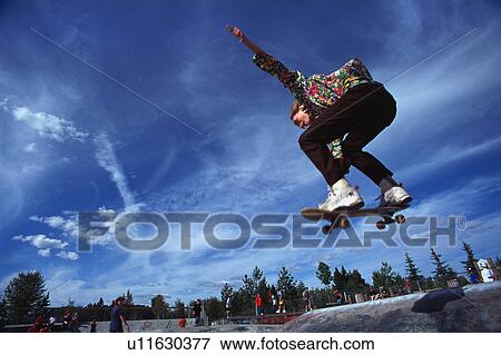 Stock Photo - Boarder performing stunt at skate park. Fotosearch