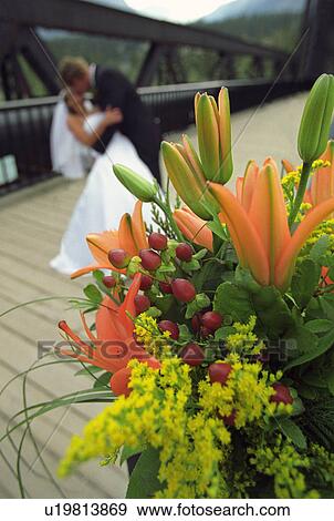 Bouquet of flowers with bride and groom kissing in the background View Large Photo Image Stock Photo - Bouquet of flowers with bride and groom kissing in the background. Fotosearch