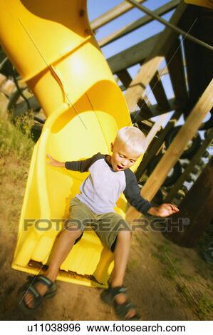 Boy goes down a slide View Large Photo Image Stock Photograph - Boy goes down a slide. Fotosearch
