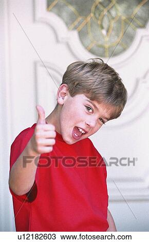 Boy with thumbs-up in front of door View Large Photo Image Stock Image - Boy with thumbs-up in front of door. Fotosearch