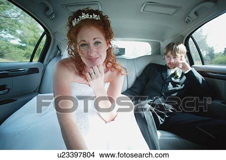 Picture - Bride leans forward in car. Fotosearch