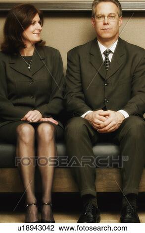 Stock Image - Business couple sitting on bench. Fotosearch