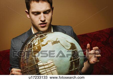 Stock Image - Businessman looking at a globe. Fotosearch