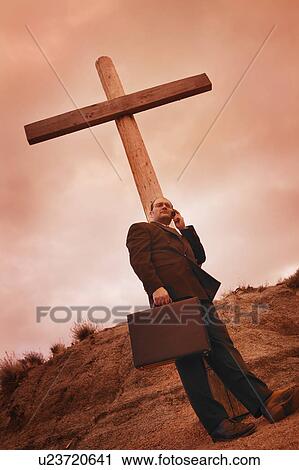Businessman on phone leaning on a cross View Large Photo Image Stock Image - Businessman on phone leaning on a cross. Fotosearch
