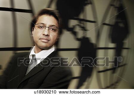 Stock Image - Businessman standing in front of world map. Fotosearch