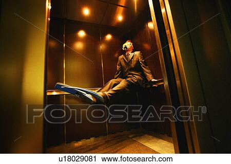 Stock Image - Businessman with flippers & goggles on in elevator. Fotosearch