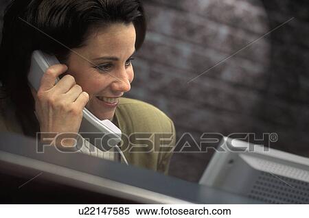 Businesswoman on the phone in front of computer View Large Photo Image Stock Photography - Businesswoman on the phone in front of computer. Fotosearch