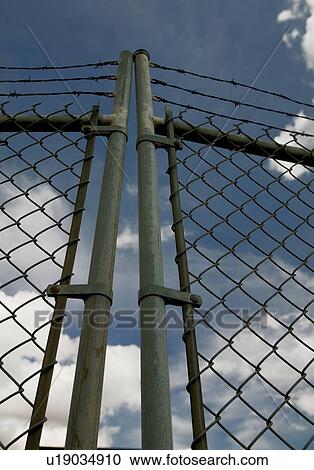 Stock Image - Chain link gate with barbed wire. Fotosearch