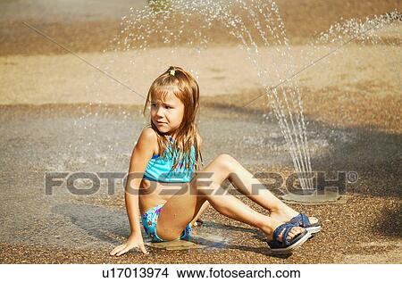 Picture - Child sits beside sprinkler. Fotosearch