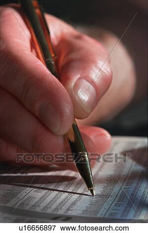 Stock Photo - Closeup of man's hand and pen circling Investment in newspaper. Fotosearch
