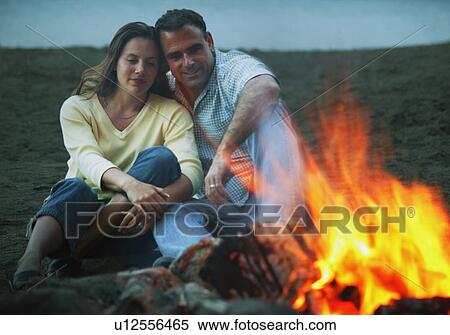 Couple keep warm by campfire View Large Photo Image Stock Photography - Couple keep warm by campfire. Fotosearch