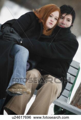 Stock Photograph - Couple sitting on bench in winter. Fotosearch