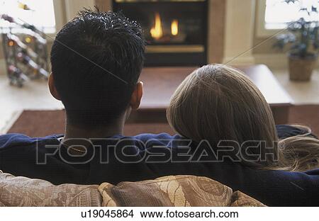 Couple snuggles by fireplace View Large Photo Image Picture - Couple snuggles by fireplace. Fotosearch